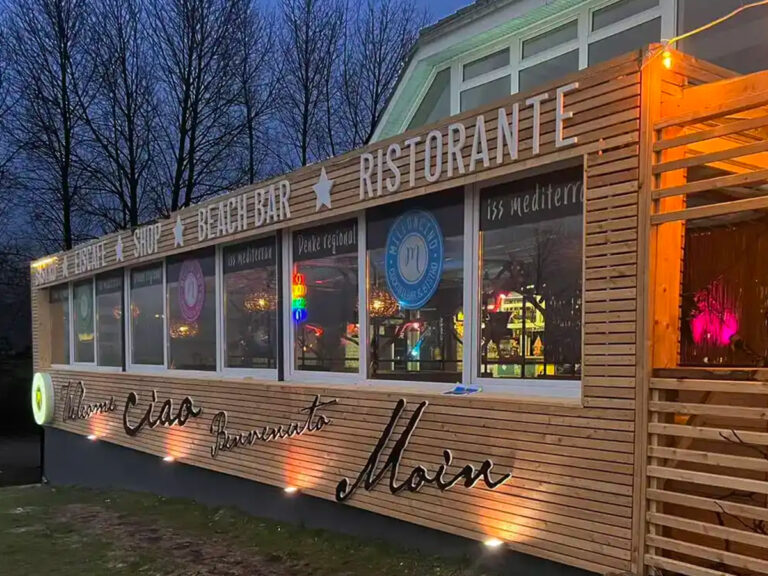 Beleuchtete Außenbeschriftung des Restaurants Milloncino an einer Holzfassade